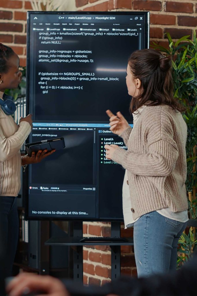 Deux Salariés De L'Agence De Développement Algos, Devant Un Écran Géant, En Train De Coder Un Programme D'Intelligence Artificielle.